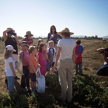 Woman speaking to a group of children at a farm