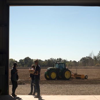 people standing in a warehouse doorway with a tractor in the background