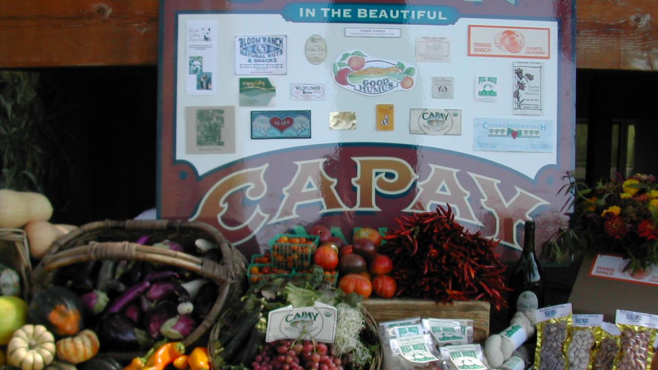 sign advertising capay valley with assorted produce in front of it