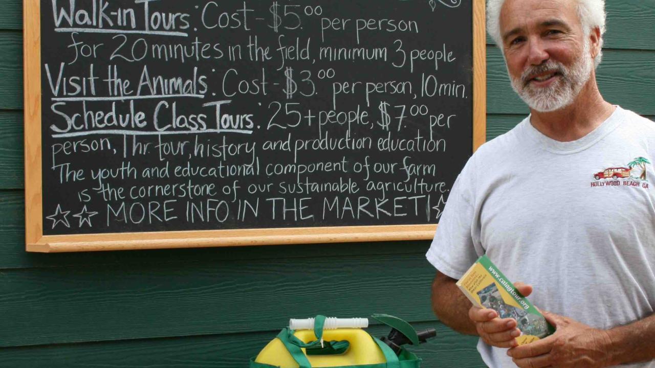 man standing in front of farm tours sign