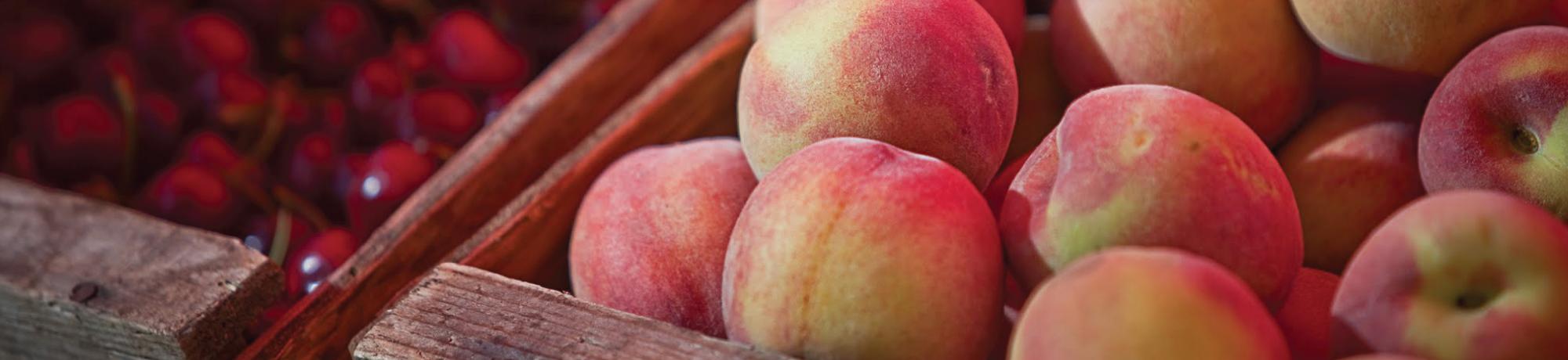 bins of peaches and berries at a market